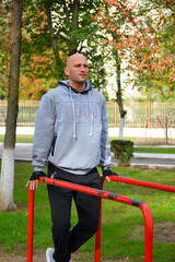 young man doing sports outdoors in a public park, doing an exercise on the uneven bars