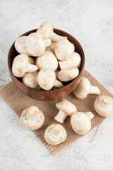 White mushrooms in a wooden cup on a piece of burlap
