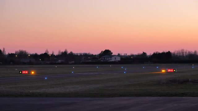 Airport lights blinking by runway sign and holding point at local airfield