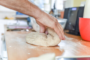Person making bread in a home kitchen adding ingredients to make the dough and then kneading it by hand