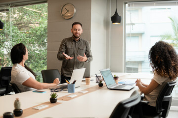 brazilian man leading presentation for teammates in coworking office. .