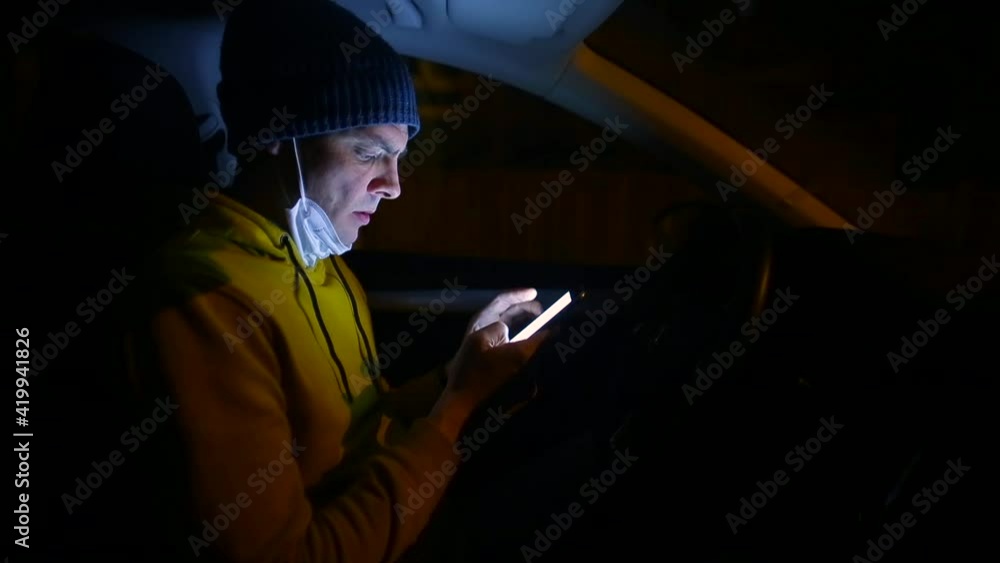 Poster a man uses a smartphone in his hands. he sits in the driver's seat of the car. procrastination while