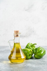 Green chili peppers with a bottle of extra virgin olive oil on marble background