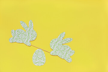 Cute Easter rabbits green on a yellow background. Decor with your own hands made of paper. Rabbits swing on swings