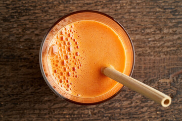 A glass of carrot juice with a bamboo straw - top view