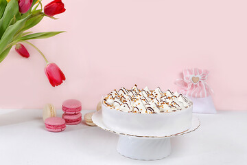 Cake with chocolate and meringue, marshmallow and flowers on a light table, festive food for mother's day, wedding, birthday. Modern bakery concept, advertising space, selective focus,