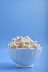 Popcorn in bowl on a blue background. Close up. Top view