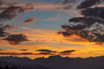 Sunset over the mountains. Dramatic sky at sunset with red, yellow and orange colors. Lausanne, Switzerland.