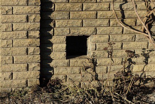 One Small Open Square Hole On A Brown Brick Wall Of An Outdoor Fence