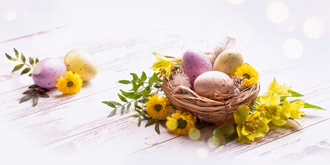 Obraz na płótnie Canvas Easter greetings. Multi-colored eggs in a nest, yellow flowers and bokeh 