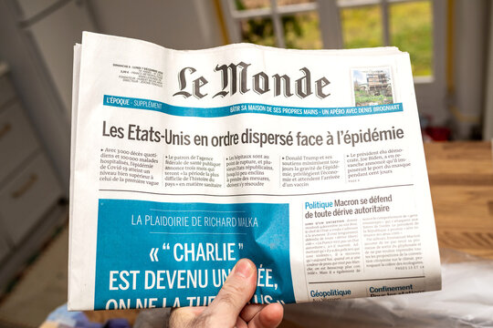 Paris, France - Dec 9 2020: POV male hand holding LE Monde French newspaper with title about United States and COVID-19 vaccine