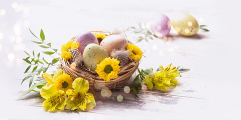 Easter greetings. Multi-colored eggs in a nest, yellow flowers and bokeh 