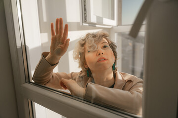 a girl beznazhёno sits on a glass door, thinks how to get out, put her hand on the glass