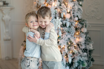 Two little brothers are playing and laughing near the Christmas tree . Family New Year unpacking gifts