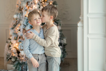 Two little brothers are playing and laughing near the Christmas tree . Family New Year unpacking gifts