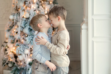 Two little brothers are playing and laughing near the Christmas tree . Family New Year unpacking gifts