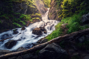 Low key landscape with waterfall in the mountains of Arkhyz. The beautiful summer landscape with mountain, forest and water stream.