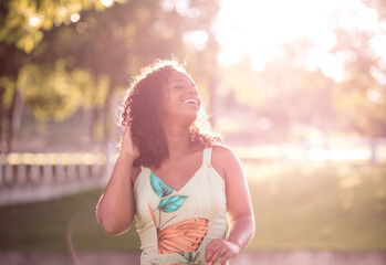 Obraz premium Portrait of a beautiful young black woman smiling with the sunlight behind.