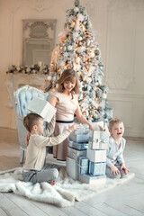 Mom and sons near the Christmas tree . Unpacking gifts .New Year