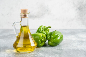 Green chili peppers with a bottle of extra virgin olive oil on marble background