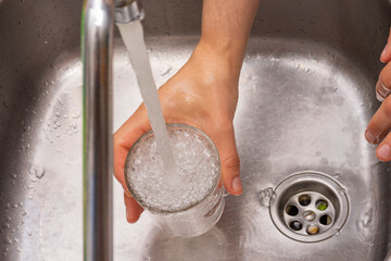 Llenando un vaso de agua en la cocina.