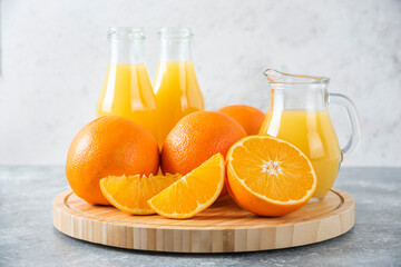 A wooden board full of juicy slices of orange fruit on stone background