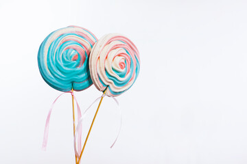 Huge colorful meringue on a stick like a popsicle on a white background isolated with copy space for message. Birthday candies for celebration. Sweet swirls or suckers for table decoration.    