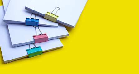 Stacking of business document with colorful binder clips on yellow background.
