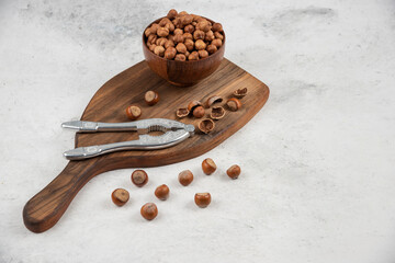 Wooden bowl of unpeeled organic hazelnut kernels on cutting board