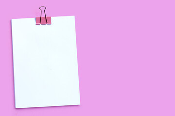 Empty paper with binder clip on pink background.
