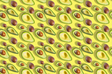 Seamless pattern of fresh ripe green avocado fruit halves with bones isolated on yellow background. Top view. Banner. Flat lay composition. Creative avocado background