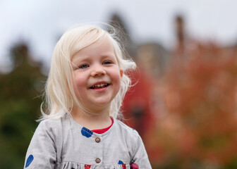 portrait of a little girl in grey dress fooling and walking around in a city