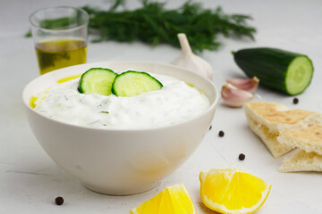 Traditional greek sauce tzatziki in a white bowl and ingredients