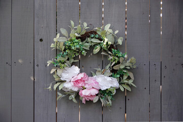 A decorative artificial flower wreath on a weathered wooden plank fence