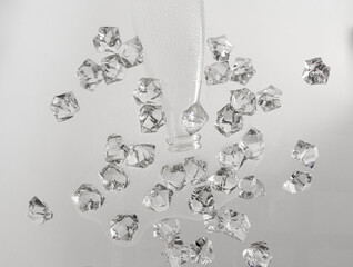 Transparent pieces of ice on a glass table. Neck from a bottle on a white background. Bottled water spilled on a glass table
