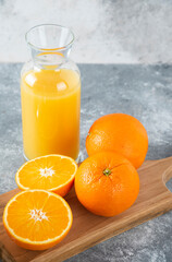Naklejka na ściany i meble Glass pitcher of juice with sliced orange fruit on a wooden board