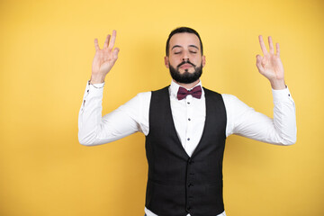Young man with beard wearing bow tie and vest relax and smiling with eyes closed doing meditation gesture with fingers