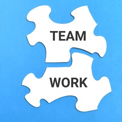 Teamwork concept. White jigsaw puzzles written TEAMWORK isolated on blue background.