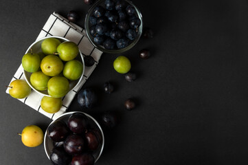 Black and green plums in white ceramic saucer in the kitchen