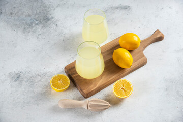 Obraz na płótnie Canvas Two glass cups of tasty lemonade on a wooden board