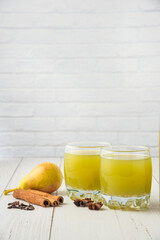 Pear and juice in glass cups on the wooden table