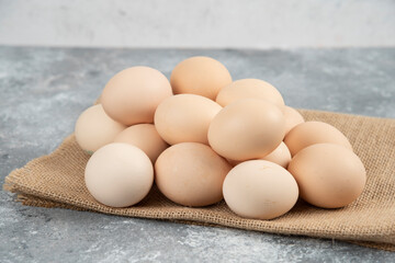 Pile of organic uncooked eggs with tablecloth on marble surface