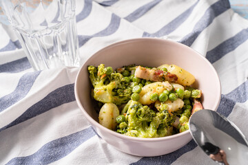 Top view on fresh prepared broccoli with gnocchi in bowl on the table - homemade healthy food in bright light with copy space