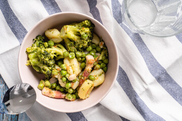 Top view on fresh prepared broccoli with gnocchi in bowl on the table - homemade healthy food in bright light with copy space