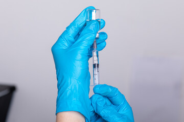 Doctor scientis in protective gloves holding glass vial with injection liquid. Vaccination against influenza and coronavirus