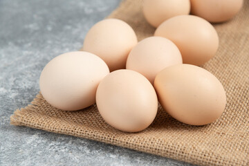 Pile of organic uncooked eggs with tablecloth on marble surface