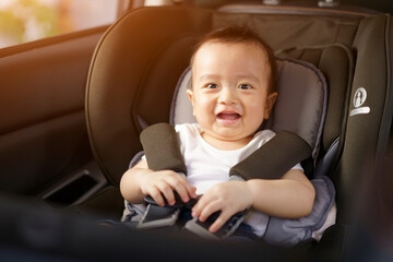 Asian little baby happy and fun while fastened belt and seat in the safety car seat. A boy looking his mother and smile in a car.