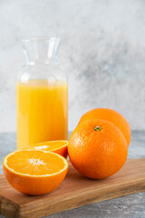 Fototapeta na wymiar Glass pitcher of juice with sliced orange fruit on a wooden board