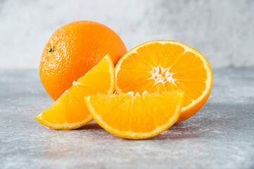 Sliced and whole juicy orange fruits on stone background