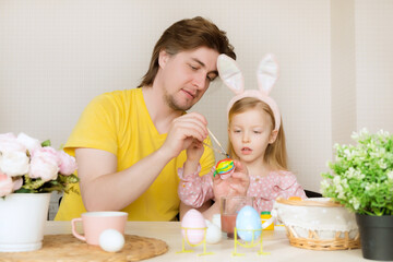 Obraz na płótnie Canvas Easter, family, holiday and children concept. Father and daughter painting eggs. Happy family preparing for Easter